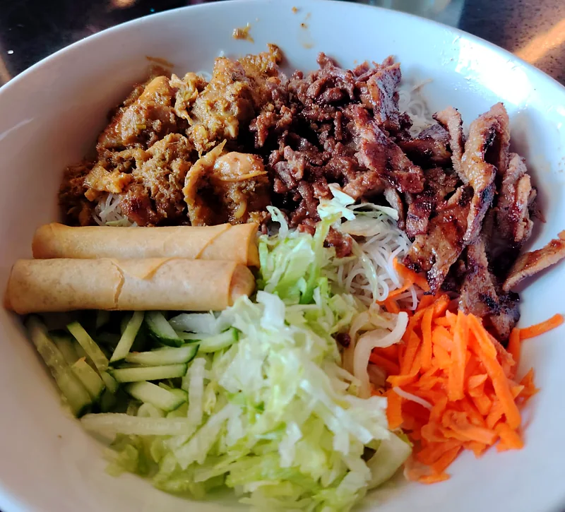 Vermicelli bowl with grilled meats and spring rolls