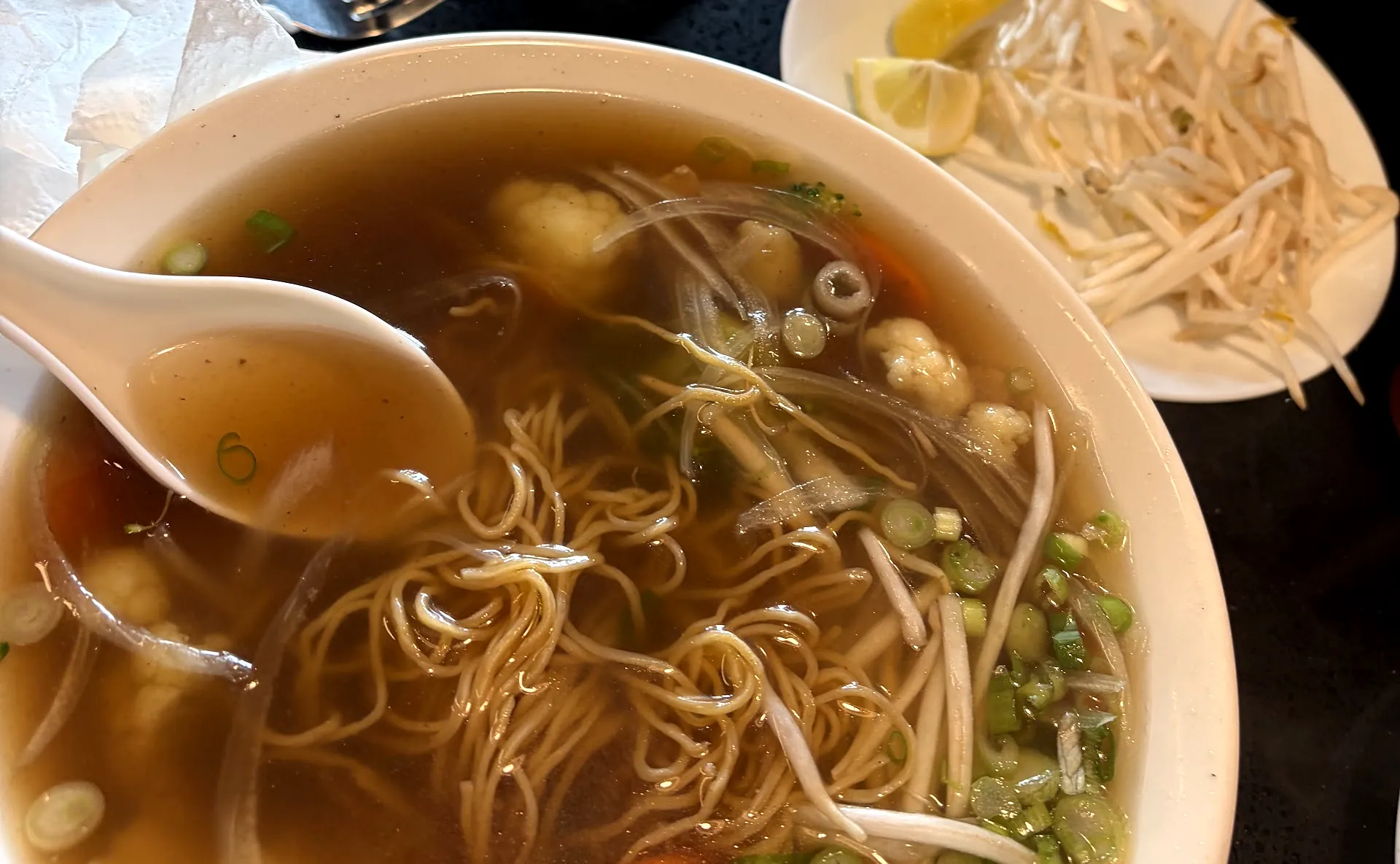 Bowl of beef pho with spring rolls, bean sprouts and lime at Pho House Chappelle